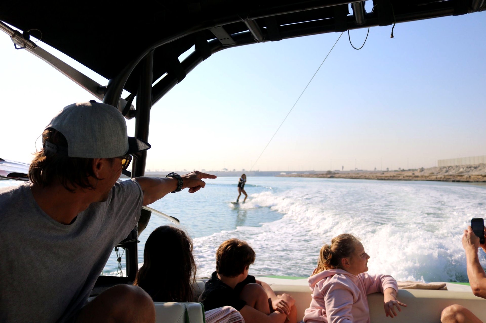 Eywoa coach pointing out a wakesurfer to kids watching from the boat near Yas Island, Abu Dhabi