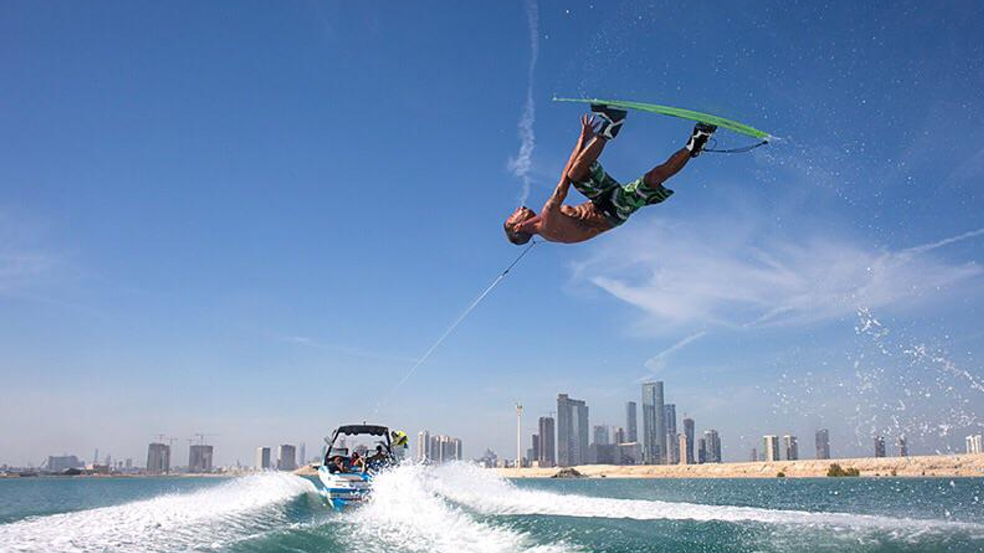 Wakeboarder jumping the wake behind a boat near Yas Island, Abu Dhabi