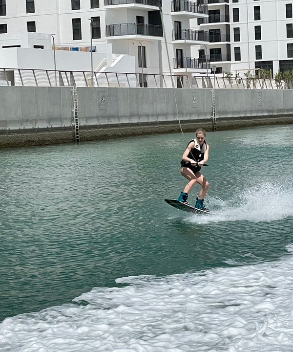 Child taking first wakeboarding steps with an Eywoa coach in Abu Dhabi